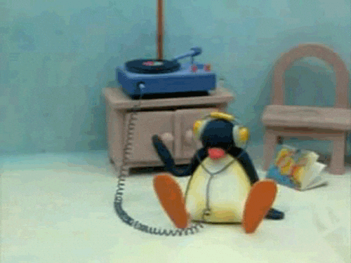 Claymation penguin sitting by a toy record player, listening with headphones