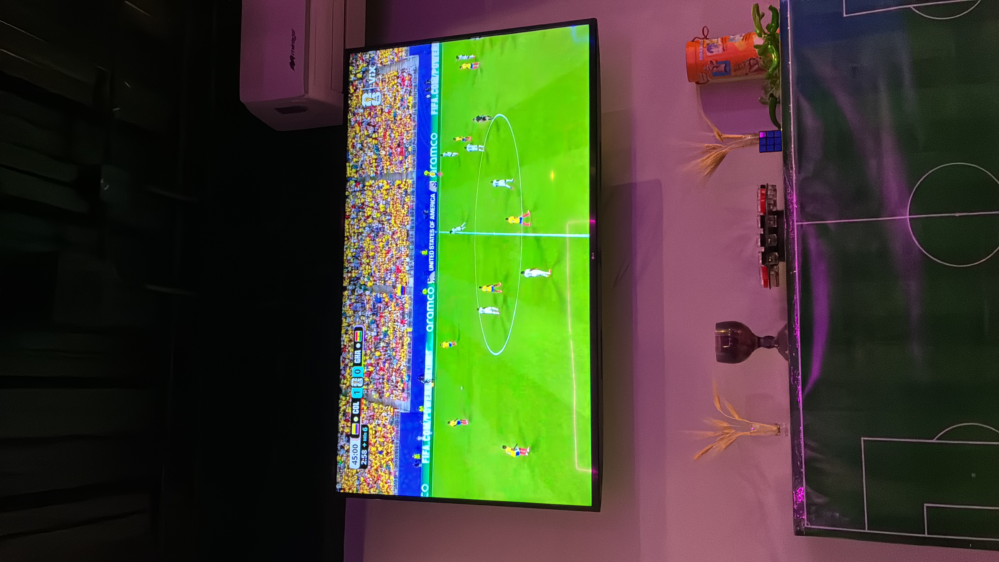 TV showing a World Cup match between Colombia and Ghana in a living room, with plants and a Rubik's cube nearby