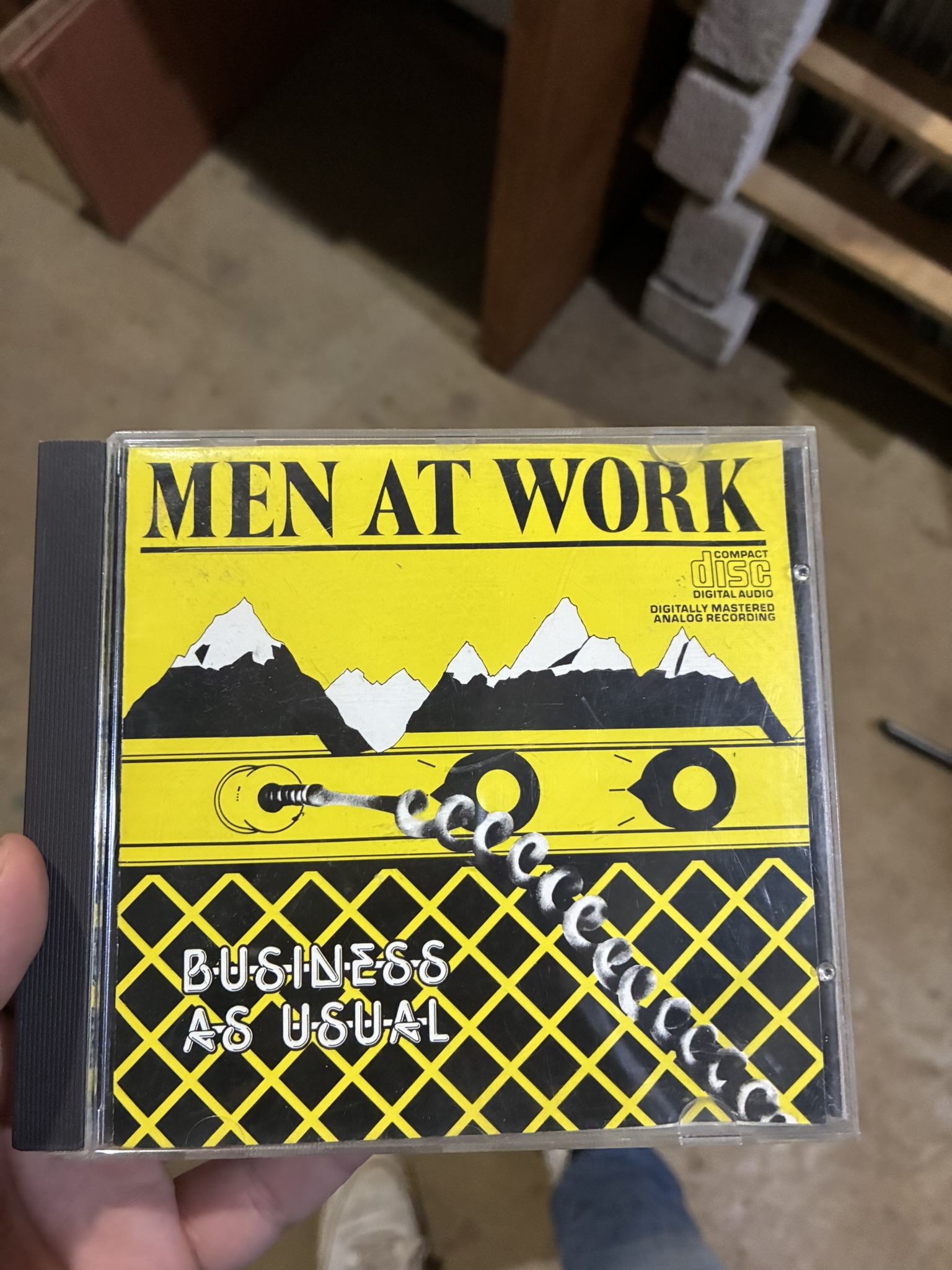 A Men at Work 'Business As Usual' CD held up in a garage