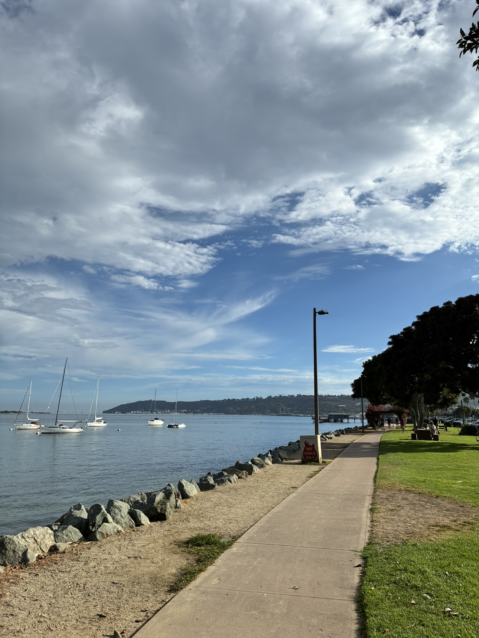 Sailboats moored in San Diego Bay next to a waterfront path