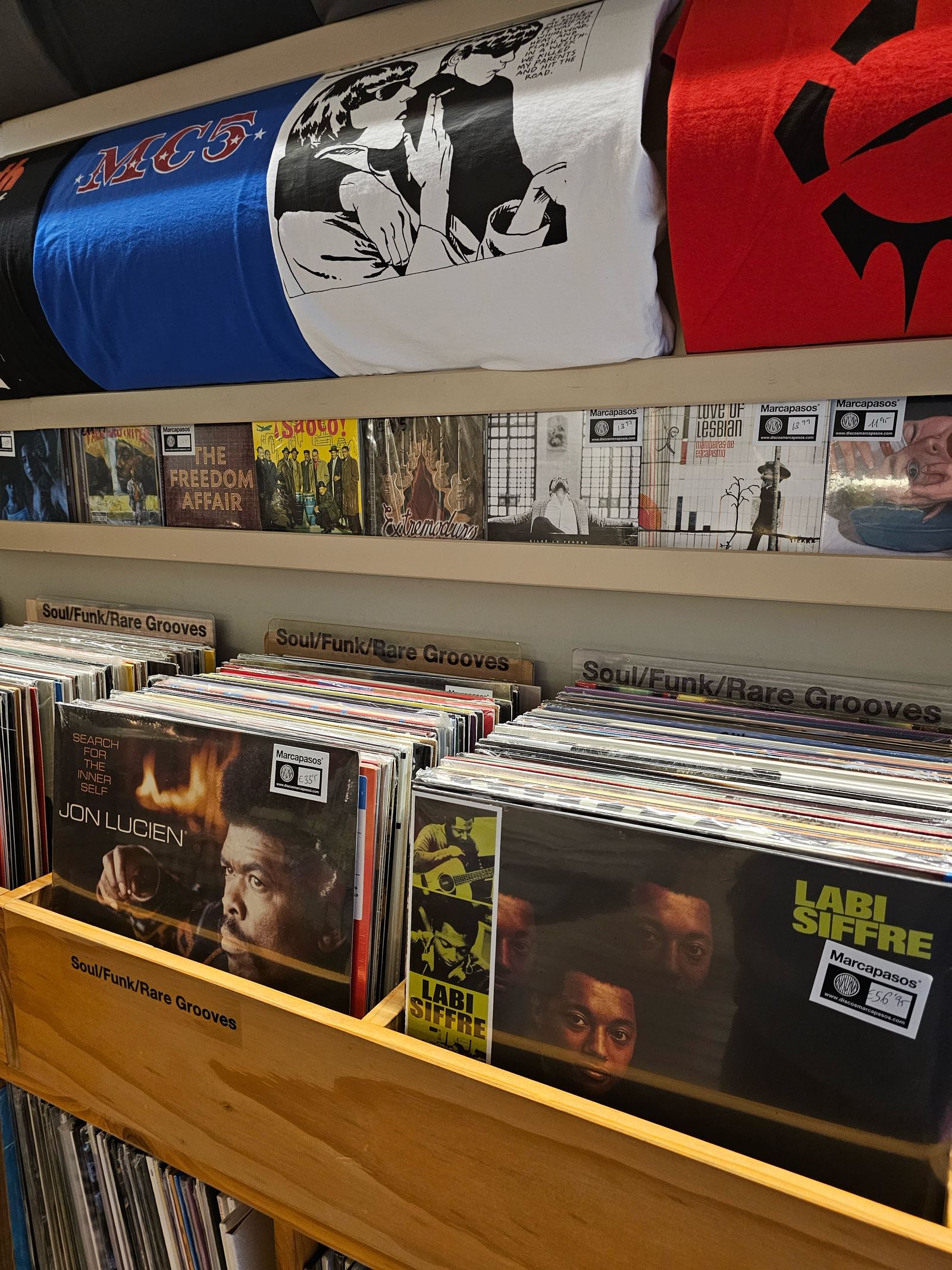 Shelves of vinyl records and band t-shirts inside a record shop in Granada