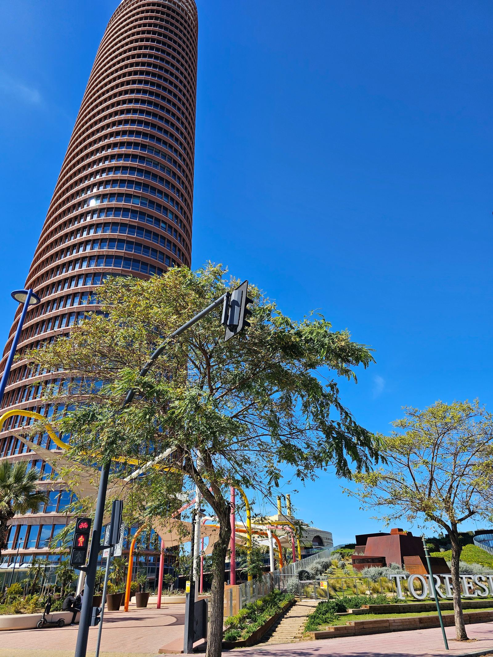 The curved brick facade of Torre Sevilla rising against a clear blue sky
